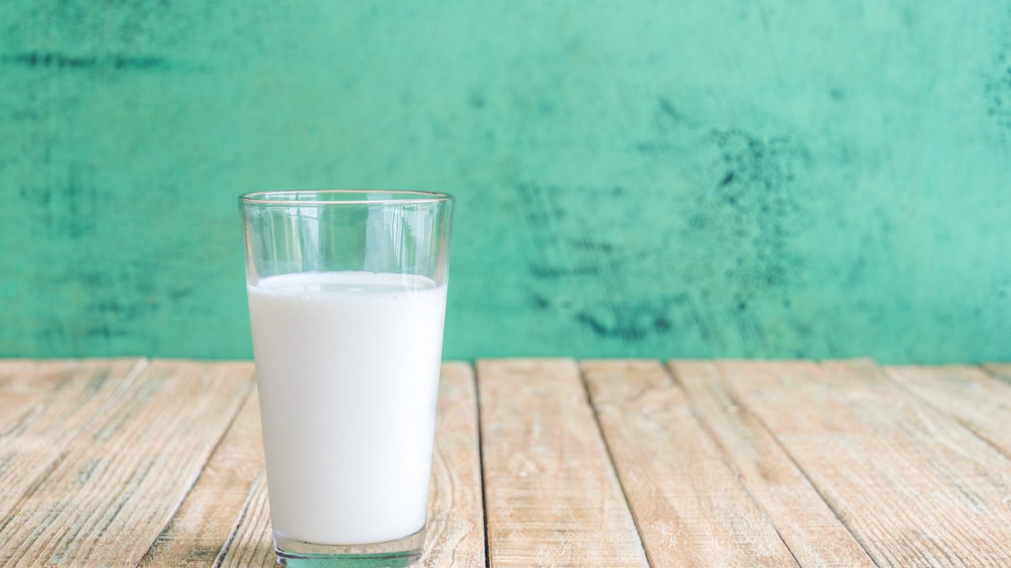 Glass of milk on a wooden table on Green background