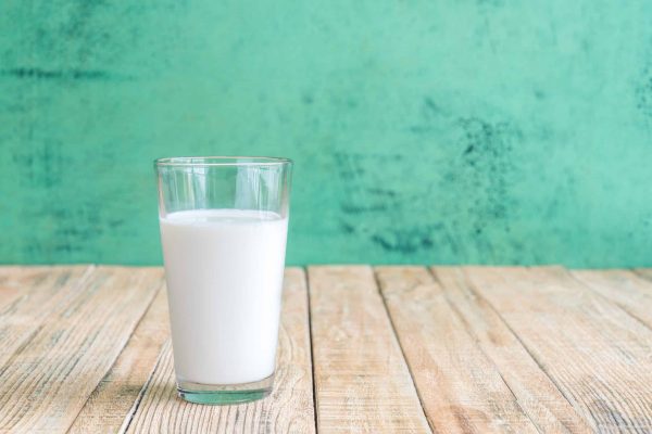 Glass of milk on a wooden table on Green background