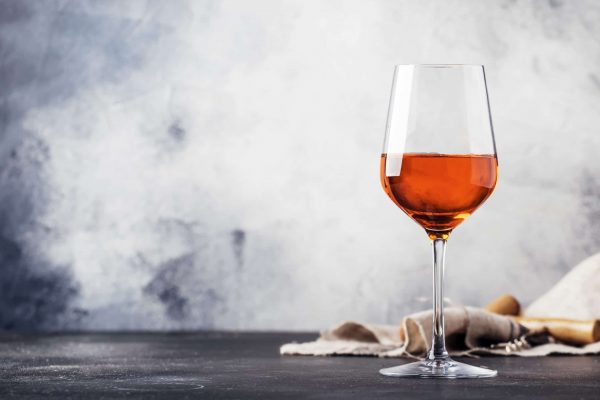 Trendy food and drink, orange wine in glass, gray table background, space for text, selective focus